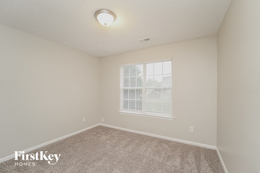 A room with a carpeted floor and a window with blinds.