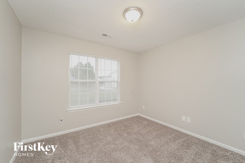 A room with a carpeted floor and a window with blinds.