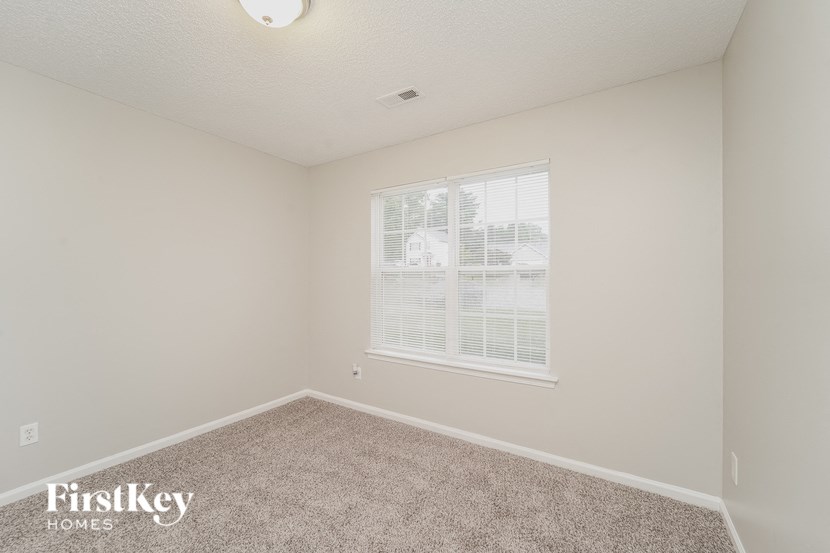A room with a carpeted floor and a window with blinds.