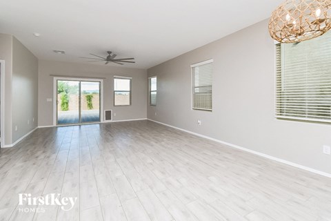 an empty living room with wood floors and a ceiling fan