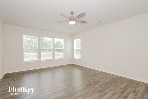 A spacious room with a ceiling fan and wooden flooring.