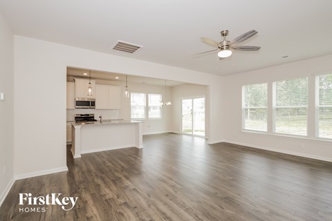 A spacious room with wooden floors and a ceiling fan.