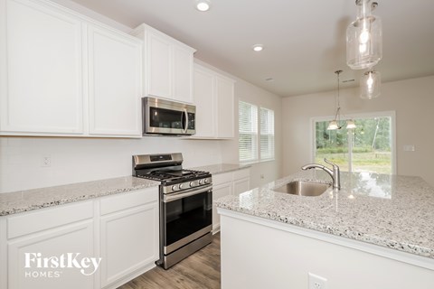 A kitchen with white cabinets and a granite countertop.