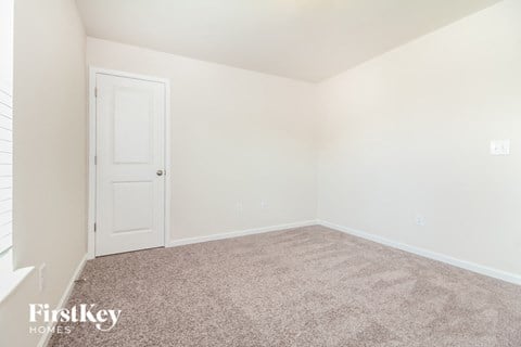 a bedroom with a carpeted floor and a white door