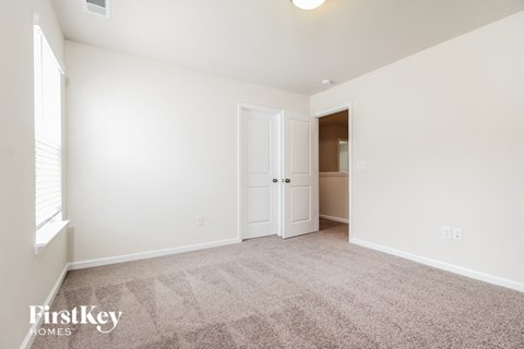 a spacious living room with carpet and a door to a closet