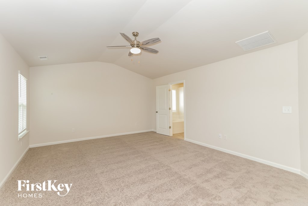 a spacious living room with carpet and a ceiling fan