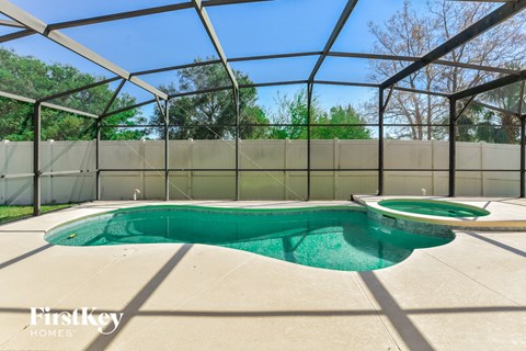 a pool in a screened in pool house with a hot tub