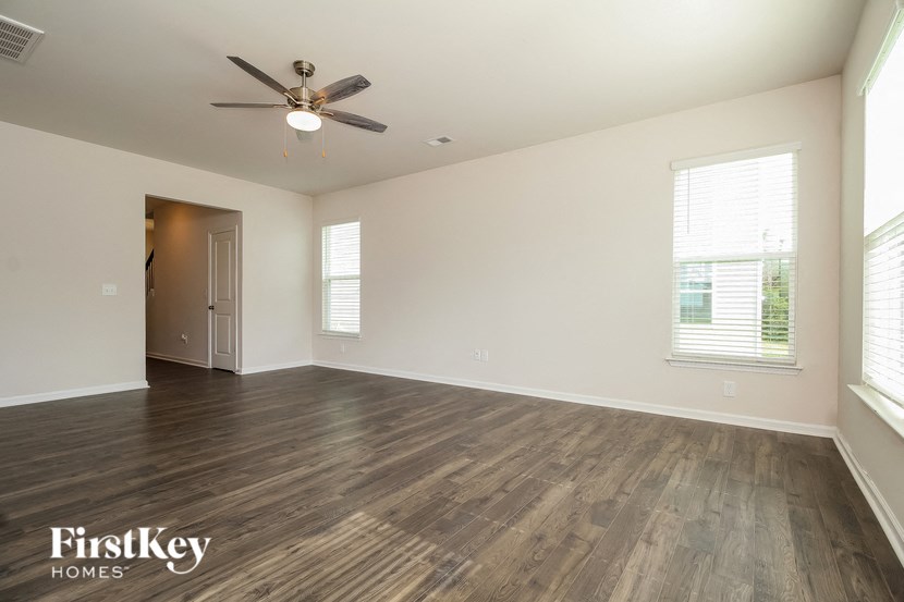 an empty living room with wood flooring and a ceiling fan