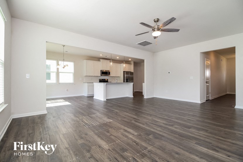 an empty living room and kitchen with a ceiling fan