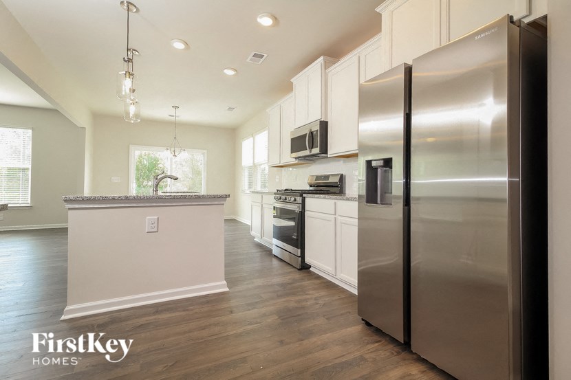 a large kitchen with stainless steel appliances and white cabinets