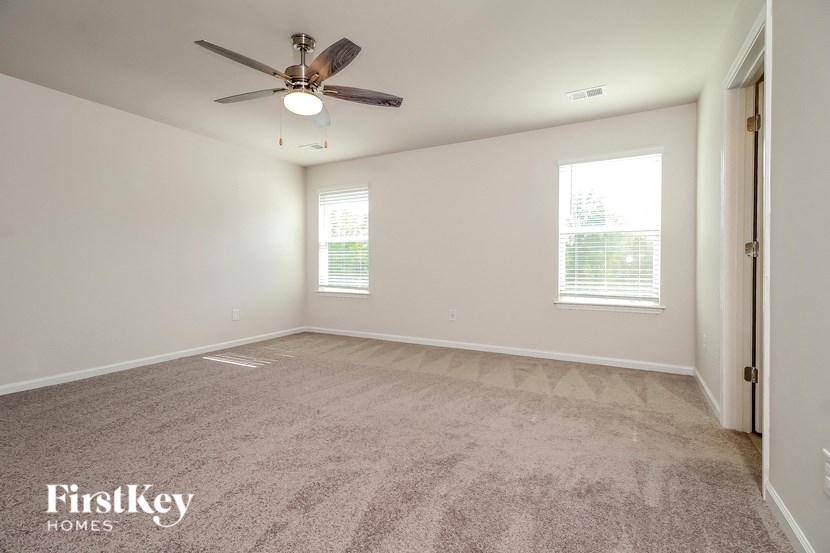 an empty living room with a ceiling fan and a window