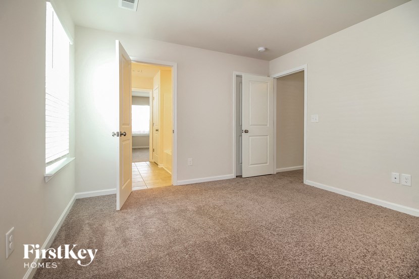 a bedroom with a carpeted floor and a door to a bathroom