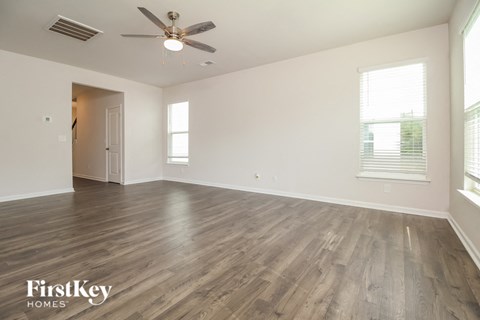 an empty living room with wood flooring and a ceiling fan