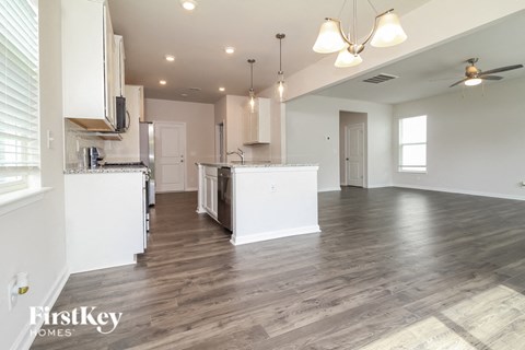 the kitchen and living room of a new home with white walls and wood flooring