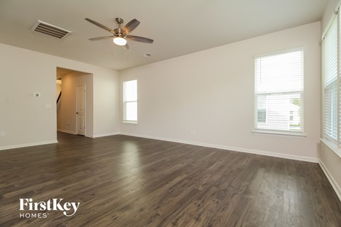 A spacious room with wooden flooring and a ceiling fan.