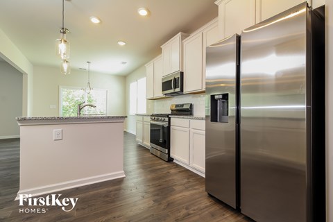 A kitchen with a stainless steel refrigerator and wooden floors.