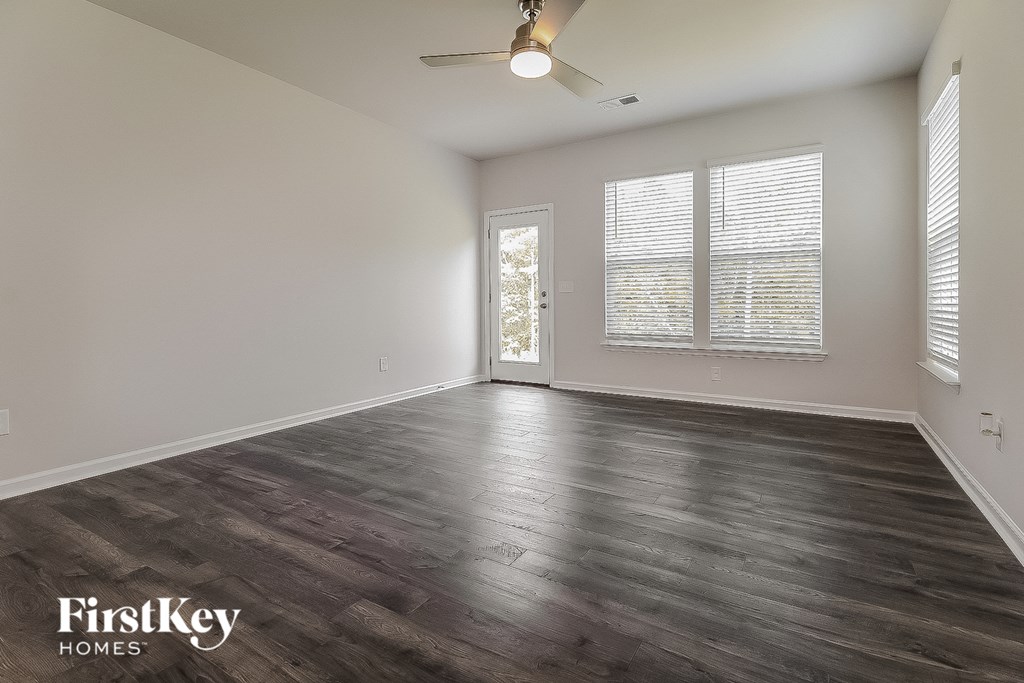 the spacious living room with wood flooring and a ceiling fan