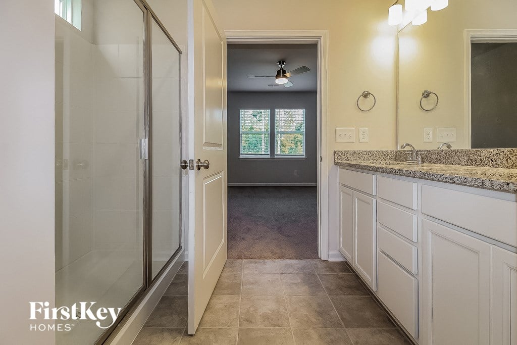 a bathroom with white cabinets and a shower and a sink