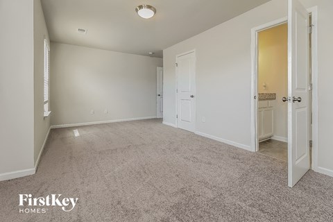 a spacious living room with carpet and a door to a bathroom