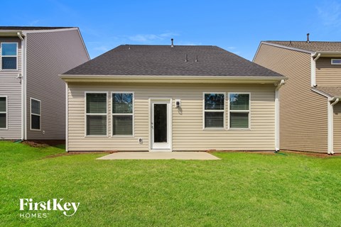 the front of a house with a grassy yard and two neighboring houses