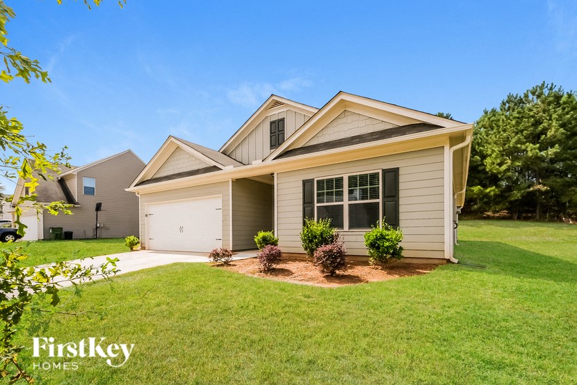 A house with a garage and a tree in front of it.