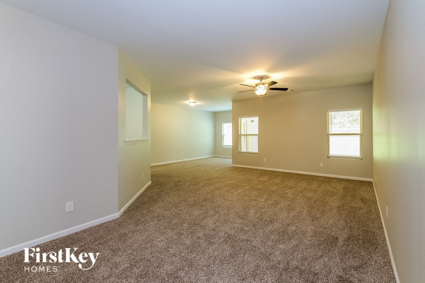 A spacious room with a carpeted floor and a ceiling fan.