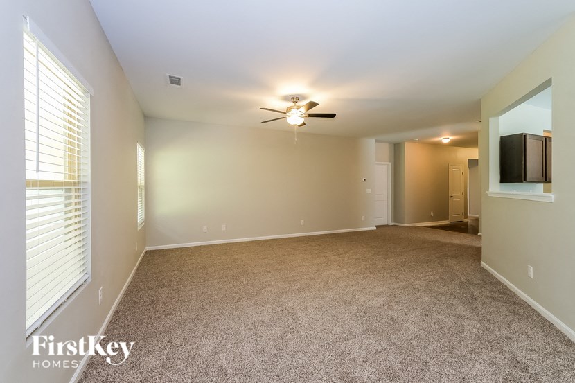 A spacious room with a ceiling fan and carpeted floor.
