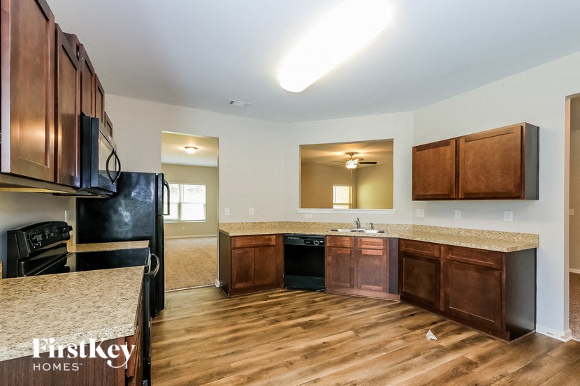 A kitchen with wooden cabinets and a black refrigerator.
