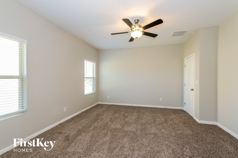 A room with a carpet floor and a ceiling fan.