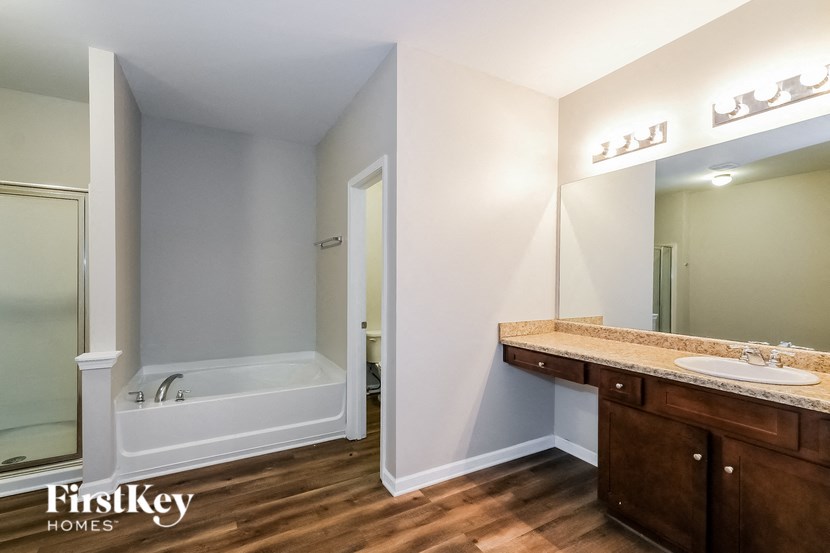 A bathroom with a tub, sink and mirror.