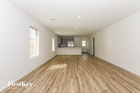 the living room and kitchen of a new home with wood floors and white walls