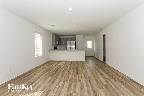 a renovated living room and kitchen with hardwood floors and white walls