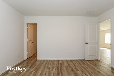 the living room of a house with white walls and wooden floors