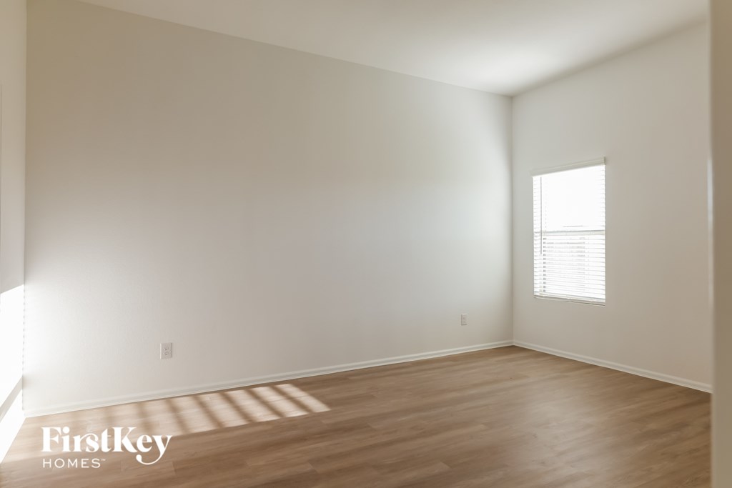 A room with wooden flooring and a window with blinds.