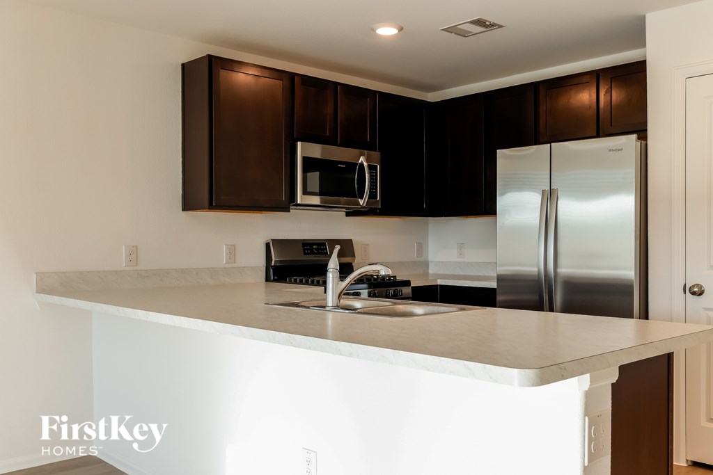 A kitchen with a stainless steel refrigerator and brown cabinets.