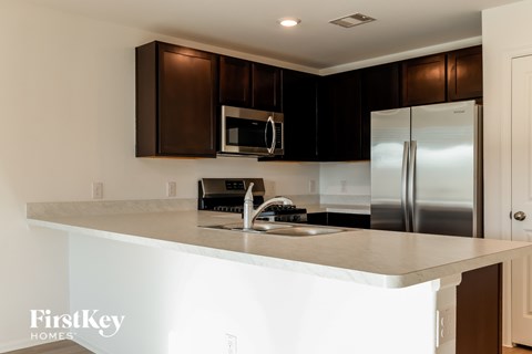 A kitchen with a stainless steel refrigerator and brown cabinets.
