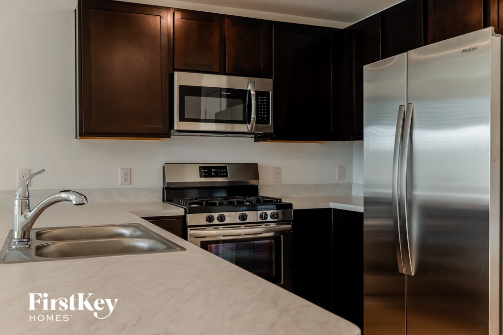 A kitchen with a stainless steel refrigerator, sink, and stove.