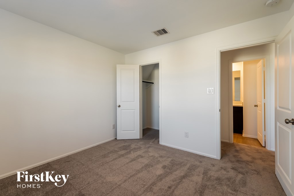 A carpeted room with a door on the left and a door on the right.