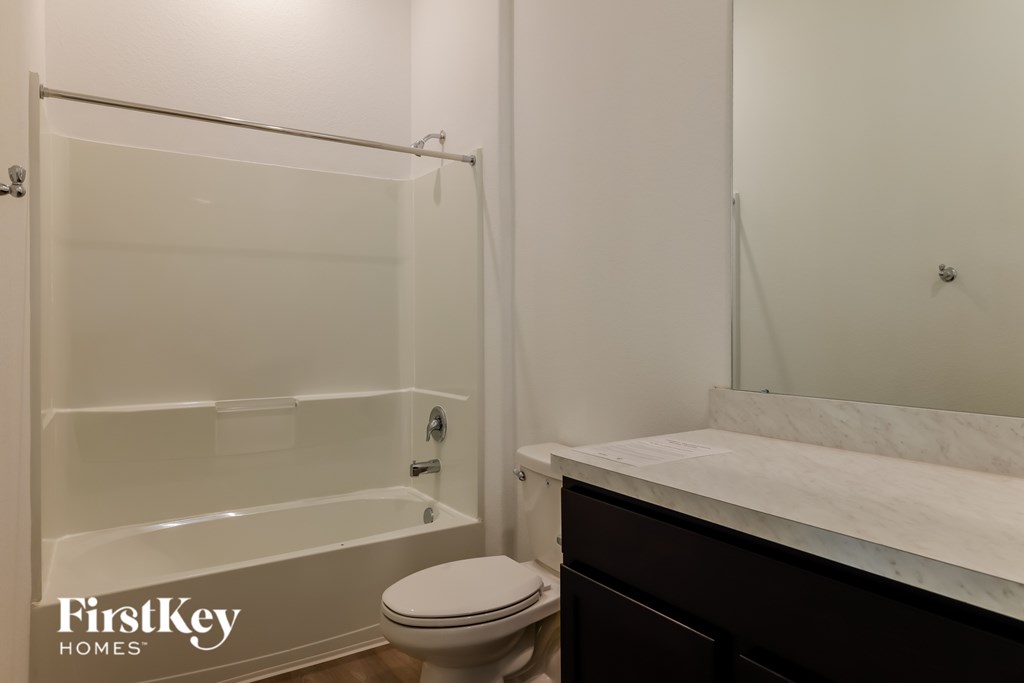 A white bathroom with a toilet, sink, and shower.