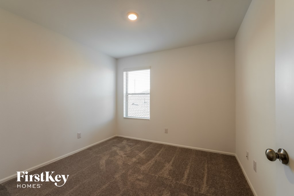 A room with a carpeted floor and a window with blinds.