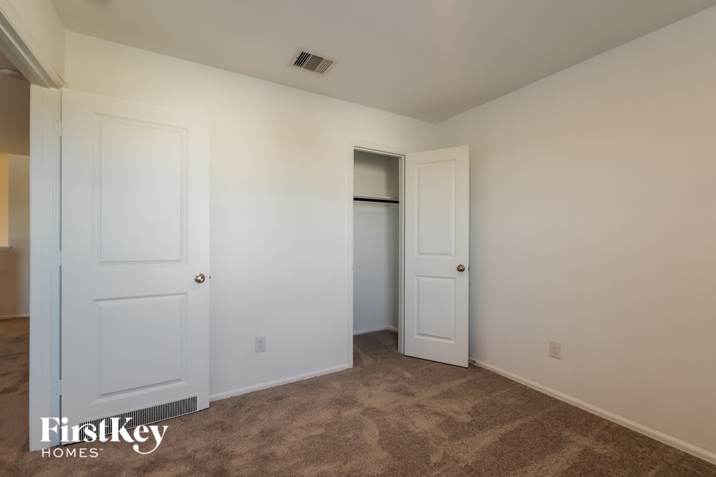 A room with a carpeted floor and two doors, one of which is open.