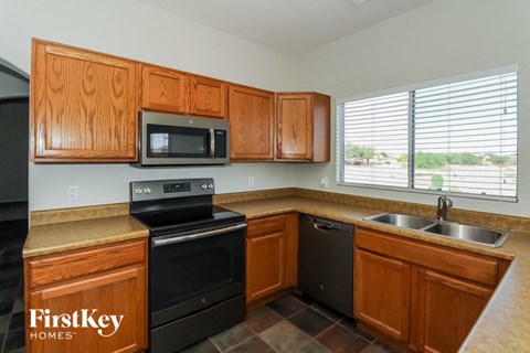 A kitchen with wooden cabinets and a black dishwasher.