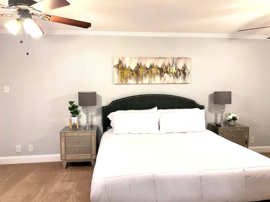 a bedroom with a large white bed and a ceiling fan