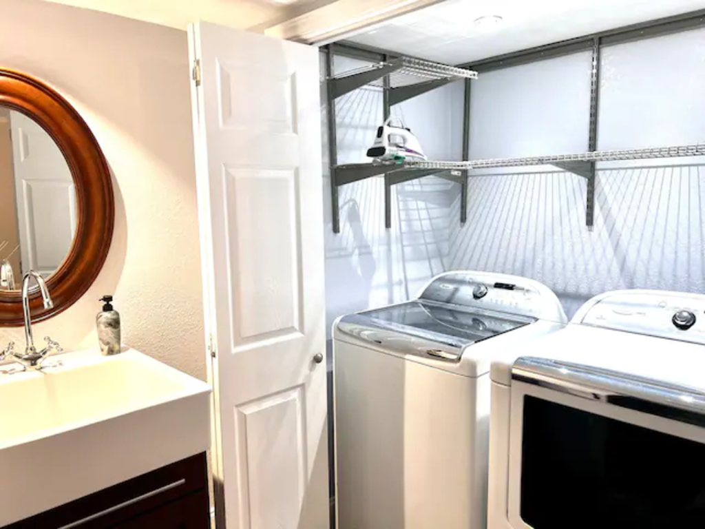 a washer and dryer in a laundry room with a sink and a mirror