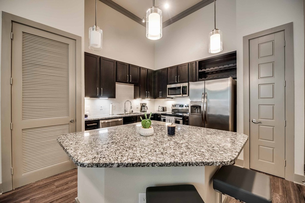 a kitchen with a granite counter top and a stainless steel refrigerator