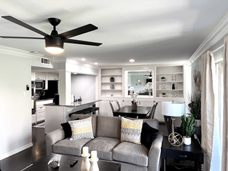 a living room and kitchen with a couch and a ceiling fan