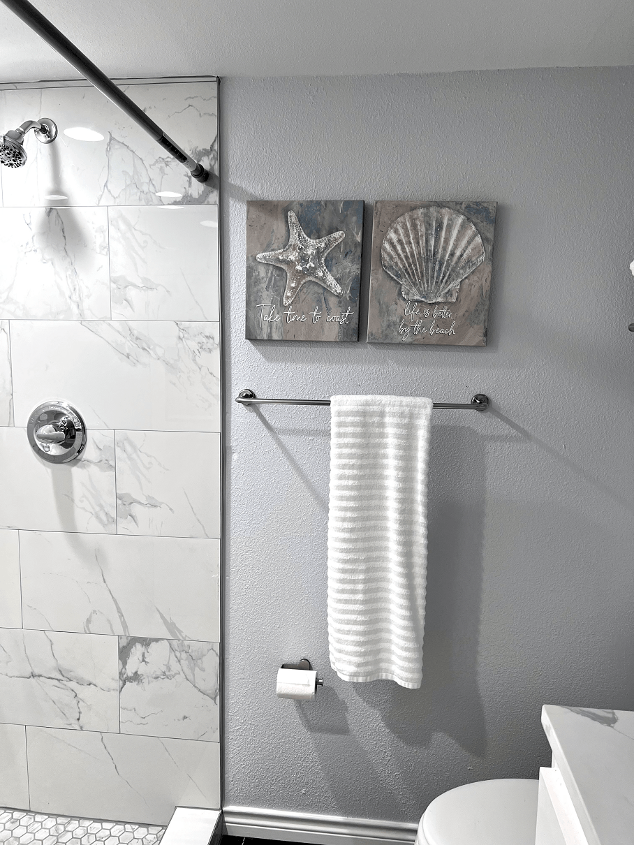 a bathroom with a shower and a white towel and a towel rack with two shells
