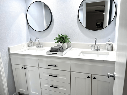 a white bathroom with two sinks and two mirrors