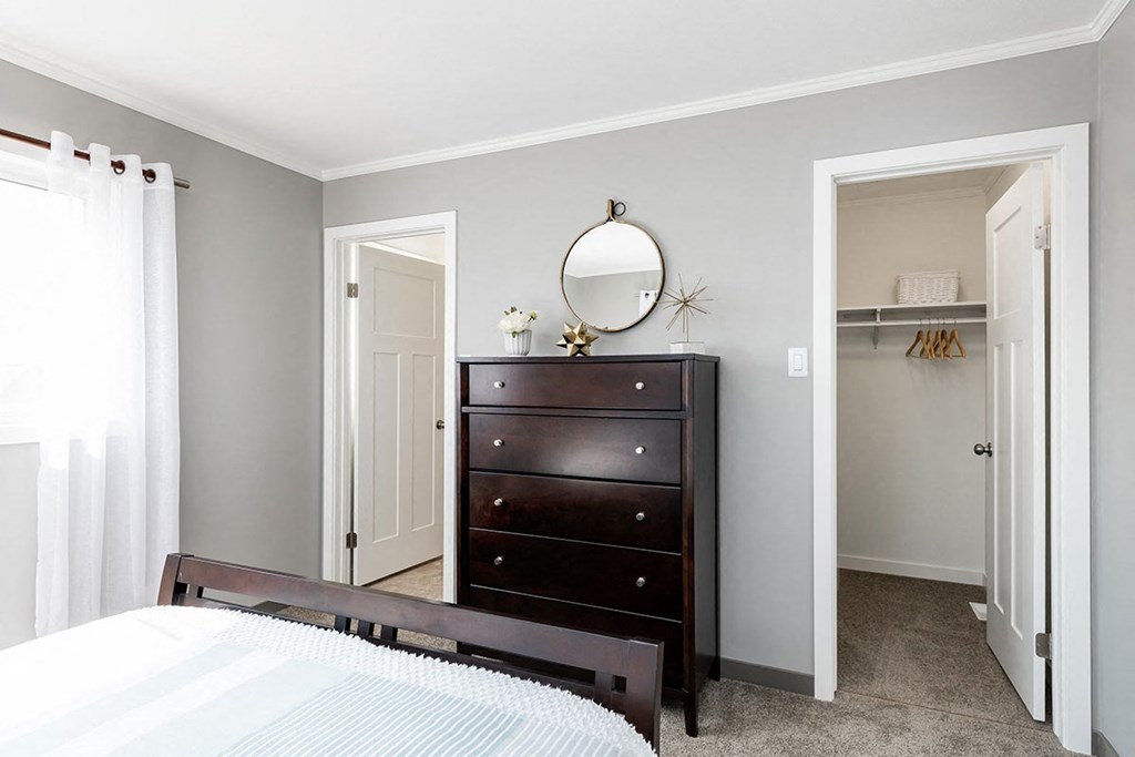 a bedroom with a dresser and a door to a closet