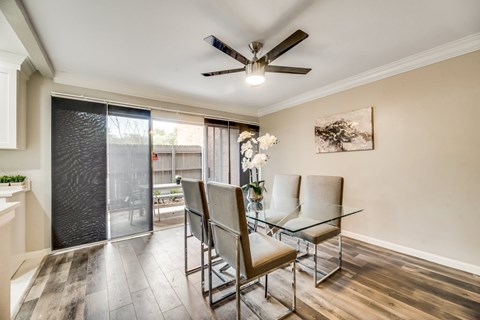 a dining room with a glass table and chairs and a ceiling fan